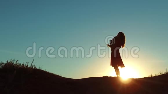 女孩举起一只小狗在日落剪影女人在大自然中和狗玩沉默的阳光友谊男人和宠物视频的预览图