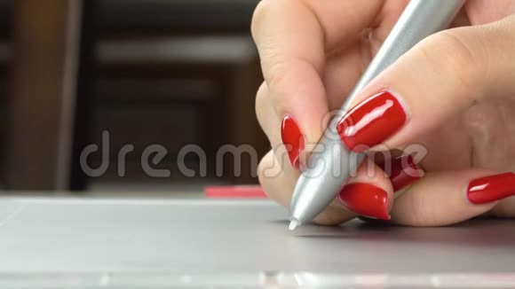 4K镜头女人的手红色指甲用笔片特写视频的预览图