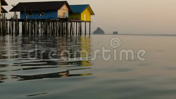 渔夫们房子在日落时从水边上方升起视频的预览图