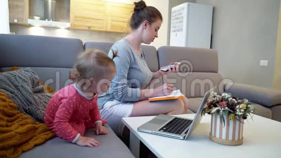 女妈妈在家里和一个婴儿一起用电脑上网视频的预览图