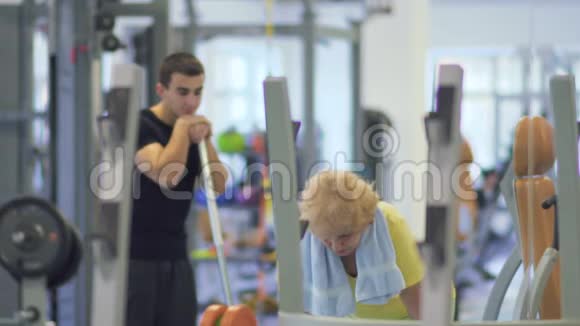 老太太在健身房用杠铃锻炼手臂视频的预览图