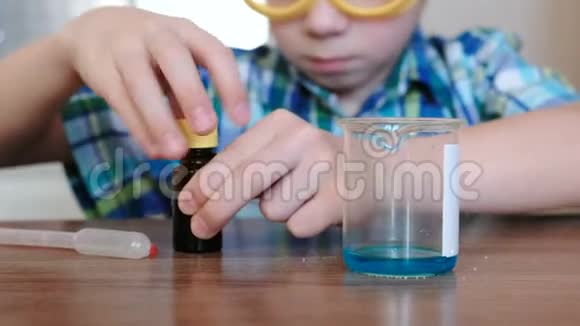 在家里做化学实验男孩用吸管把蓝色液体从罐子倒进烧杯里视频的预览图