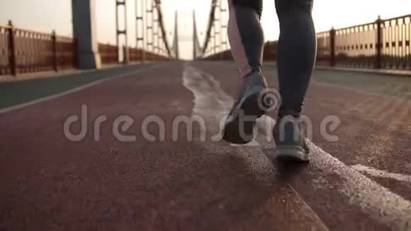 日出时在桥上慢跑的特写女性腿视频的预览图