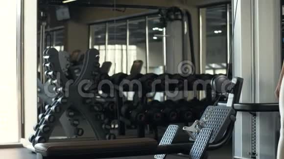 女子健美运动员坐在健身俱乐部的举重训练设备上视频的预览图