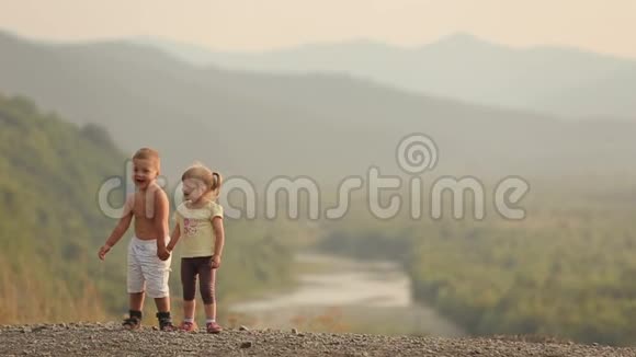 欢乐可爱的小朋友们手拉手在美丽的风景背景下接吻视频的预览图