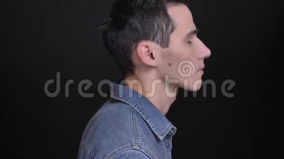 年轻白种人男性的特写镜头在黑色背景下拍摄的镜头视频的预览图