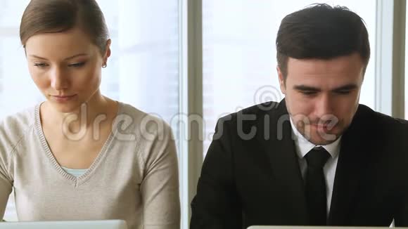 好奇的女人监视男同事看着他的笔记本电脑屏幕视频的预览图