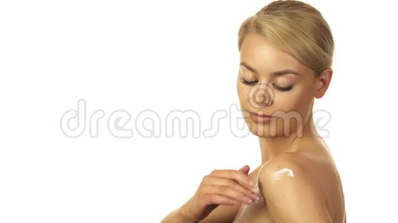 美丽的女孩正在把奶油揉进她的身体里视频的预览图