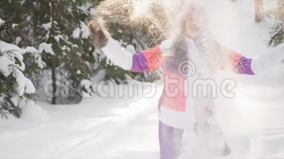 年轻女子享受阳光明媚的冬日在户外撒雪慢动作视频的预览图