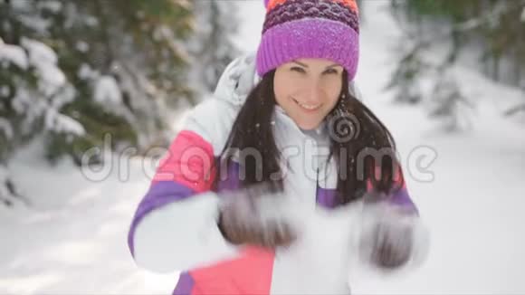 年轻女子享受阳光明媚的冬日在户外撒雪慢动作视频的预览图