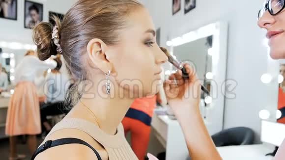 专业化妆师在时装秀前在模特脸上化妆的特写慢镜头视频的预览图