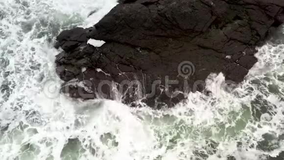 海浪拍打着黑色的岩石溅起了水花视频的预览图