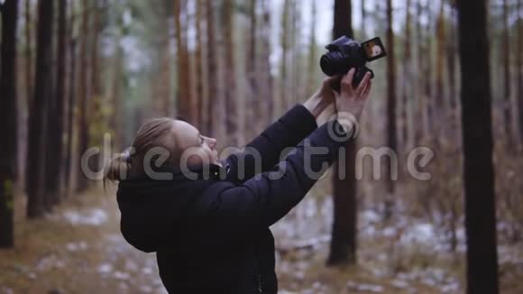 那个女孩在森林里用照相机拍照关于自然的自拍电影镜头慢动作视频的预览图