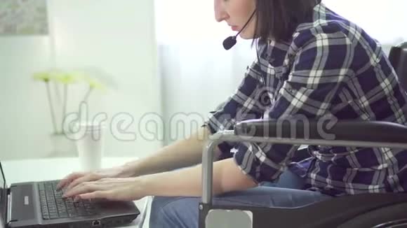 残疾青年妇女肖像轮椅家庭远程工作电脑耳机视频的预览图
