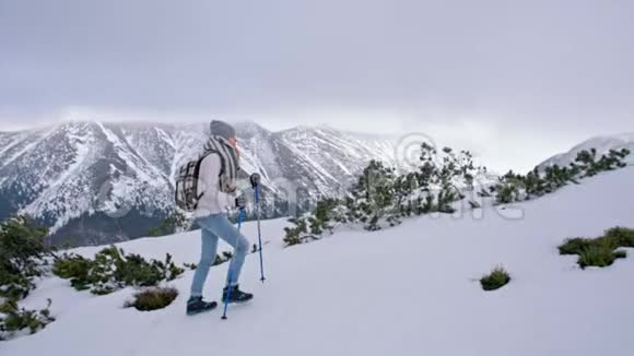 成功的女士在冬天带着雪爬山慢动作视频的预览图