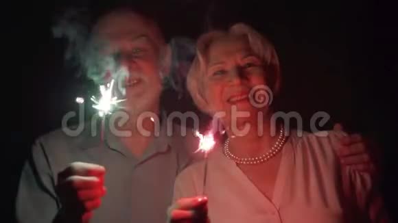 动作缓慢一对爱炫耀的老夫妇庆祝圣诞节幸福的家庭手持孟加拉灯视频的预览图