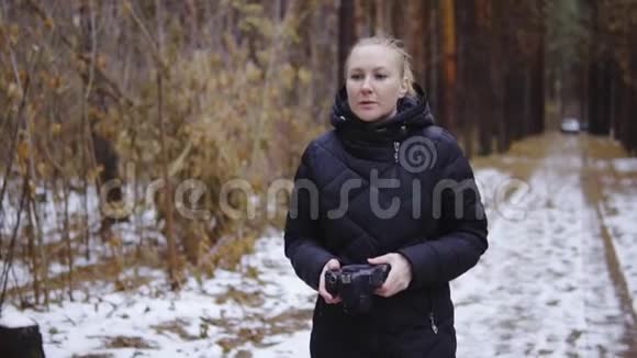 那个女孩正拿着相机在秋天的森林里散步第一次下雪电影拍摄慢镜头拍摄视频的预览图