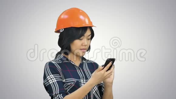带橙色头盔的女建筑师使用白色背景的智能手机视频的预览图