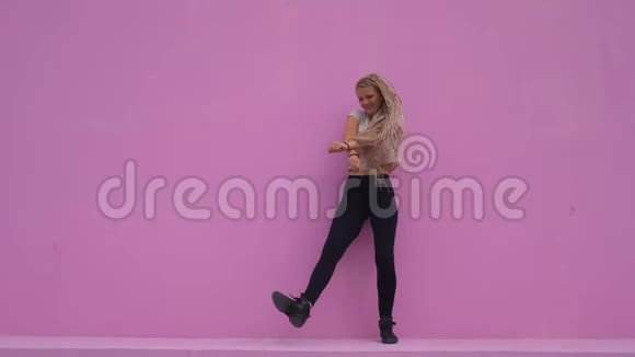 留着辫子的休闲女孩在粉红色的背景下尽情地跳舞视频的预览图