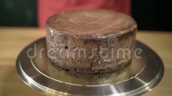 在蛋糕上倒入的液体巧克力行动融化的液体巧克力在铁架台上的圆形蛋糕上蔓延开来视频的预览图