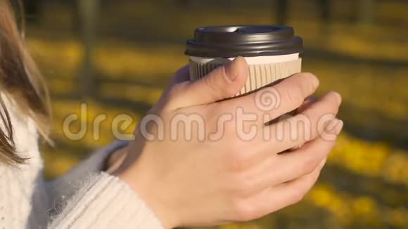 女孩温暖双手独自喝咖啡享受阳光明媚的秋天灵感视频的预览图