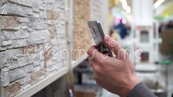 商店里有智能手机的男人挑选装修房子的材料视频的预览图