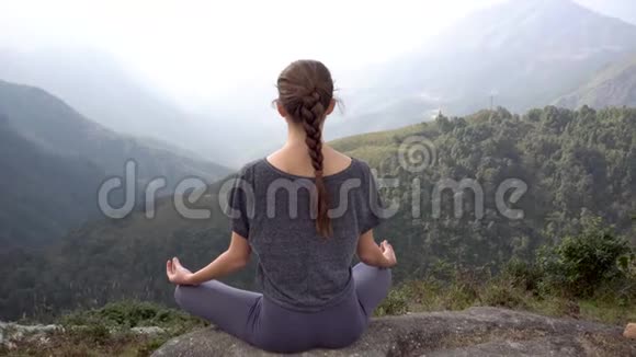在越南萨帕的山崖上瑜伽女人坐在冥想姿势帕达马萨纳视频的预览图