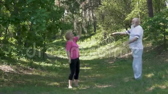 一位老年男子和一位老年妇女在夏季公园做体育锻炼视频的预览图