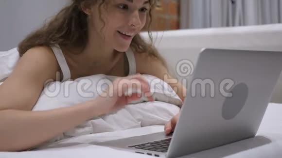 兴奋的女性在床上使用笔记本电脑进行网上视频聊天视频的预览图