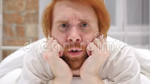躺在床上的伤心欲绝的红发胡子人脸视频的预览图