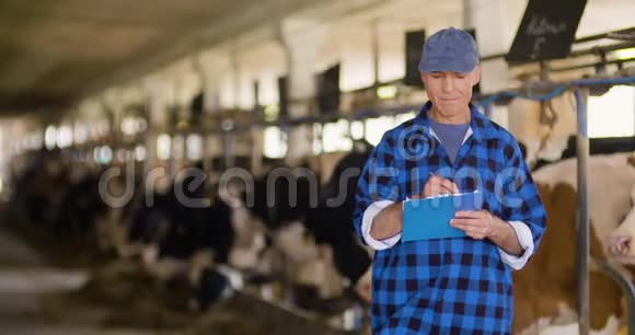 农民在马厩里写剪贴板时分析奶牛视频的预览图