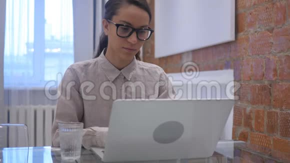 西班牙裔妇女饮水和工作笔记本电脑视频的预览图
