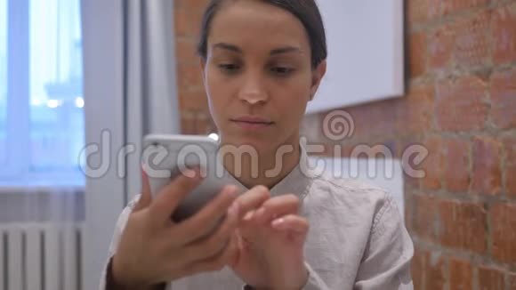 西班牙妇女在智能手机上在线浏览互联网视频的预览图