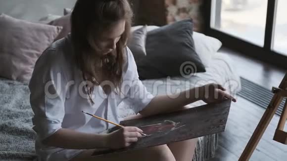 女孩艺术家在家庭工作室画了一幅画这位艺术家早上正在画一幅画视频的预览图