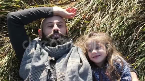 父亲和女儿躺在草地上的草地上视频的预览图