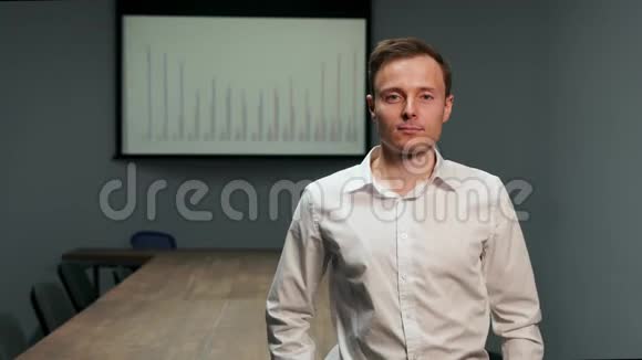 在会议桌的背景上一个穿着白色衬衫的人站在办公室里的肖像以及图表图像视频的预览图