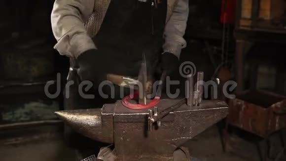 一个铁匠在车间里用铁锤敲击马蹄铁他手紧紧地拍着视频的预览图