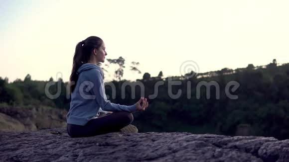 瑜伽女人坐坐冥想姿势在山崖日出视频的预览图