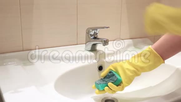 无法辨认的女人戴着黄色橡胶手套在浴室水槽里用水冲洗海绵视频的预览图