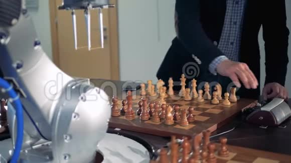 一个成年男子和一只机器人手臂正在下棋和移动棋子视频的预览图
