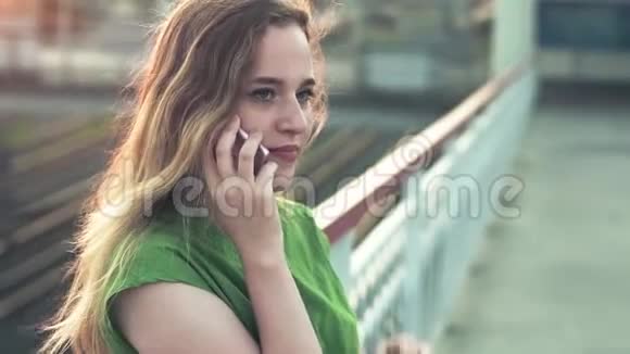 城里一个年轻女孩带着一部智能手机读留言绿色连衣裙视频的预览图