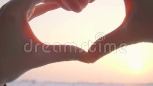 闭上女人的双手抓太阳使心形成为日落时爱的象征视频的预览图