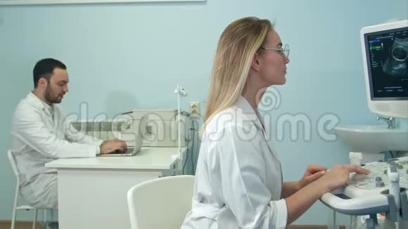 女医生用手提电脑向她的男同事口述超声波检测结果视频的预览图