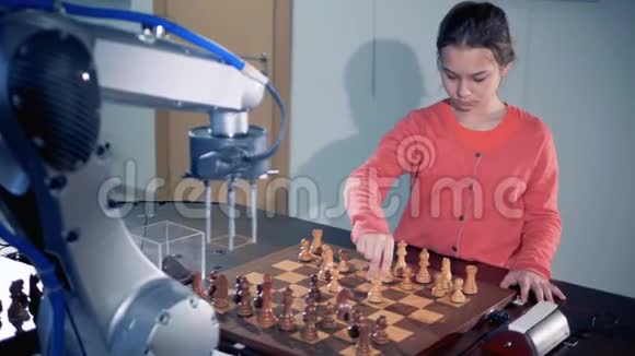 机器人手臂和一个小女孩正在移动棋子和玩视频的预览图