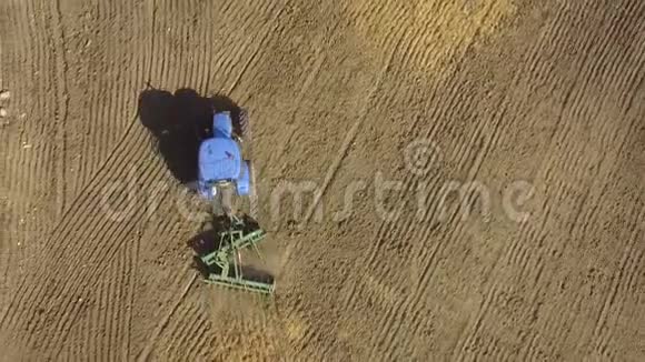 蓝色拖拉机在播后粉碎地面的空中视野视频的预览图