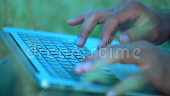 特写镜头一个坐在笔记本电脑键盘上的草地打字文本上的印第安人的手视频的预览图