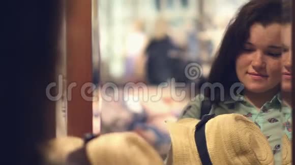 一个微笑的黑发女人在商店里戴着夏帽的肖像视频的预览图