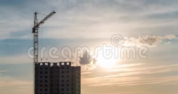 在夕阳的照耀下在多层建筑工地上工作的塔式起重机剪影的时间流逝视频的预览图
