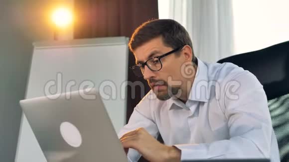 一个疲惫的商人在笔记本电脑上打字视频的预览图