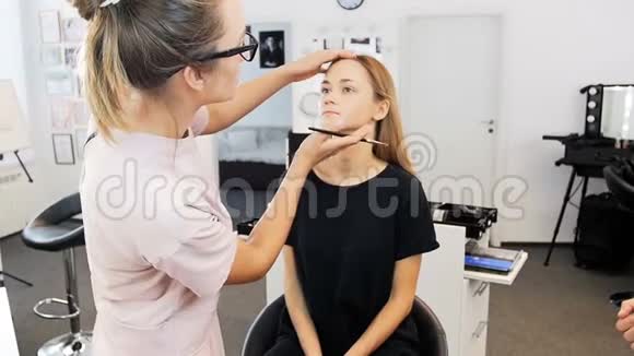 专业化妆师在时装秀前在模特脸上化妆的特写慢镜头视频的预览图